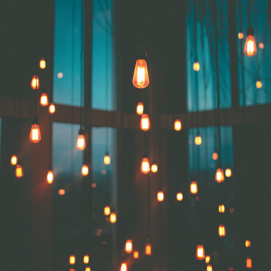 Dozens of hanging light bulbs glow in darkened room.